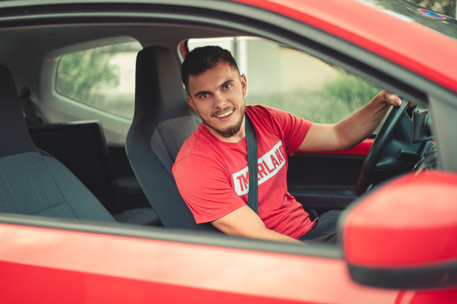 Jeune homme souriant au volant, ceinture de sécurité attachée